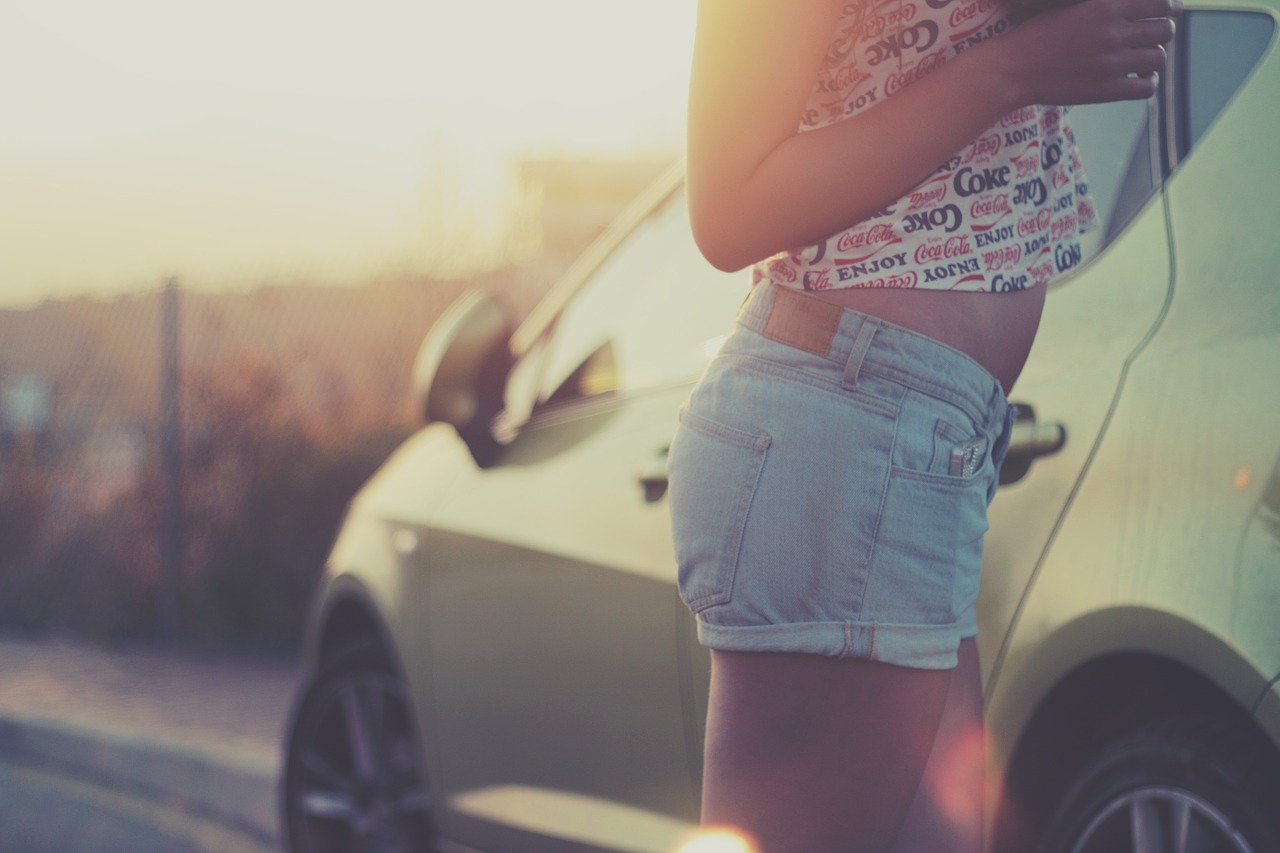 Woman in shorts and belly top as a symbol for matching clothing in the car in summer