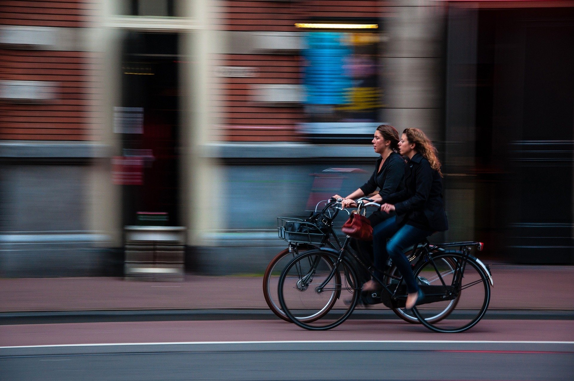 Two cyclists riding side by side in road traffic
