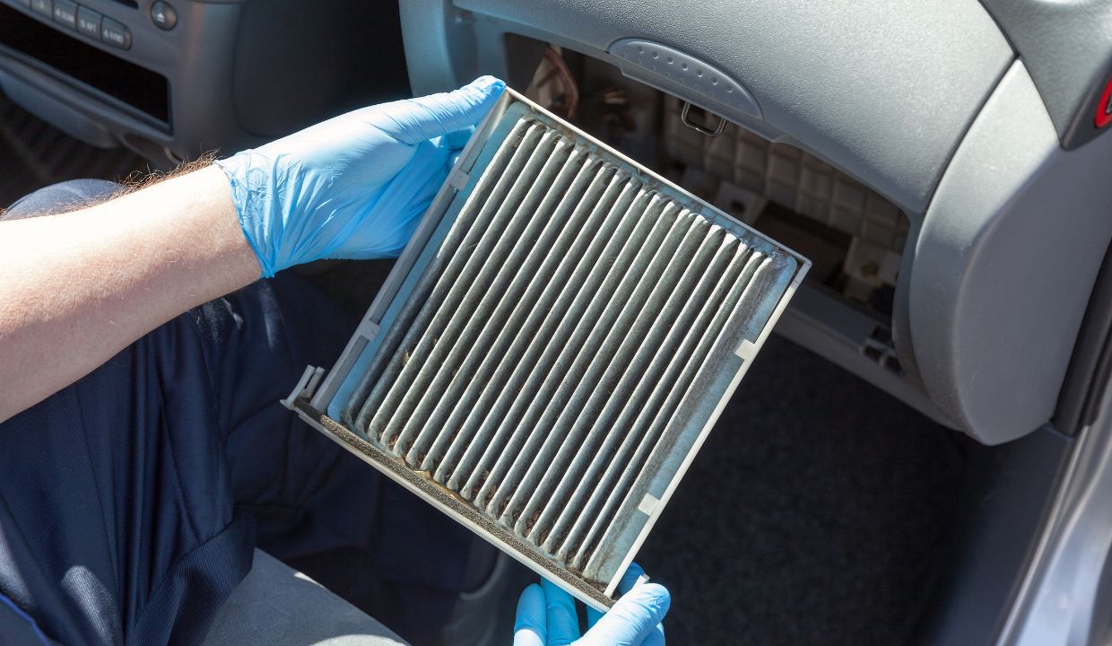 Ansicht, wie ein Innenraumfilter im Auto gewechselt wird