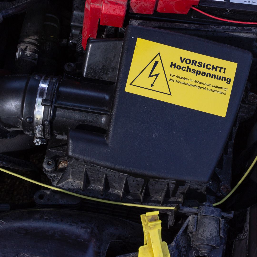 Warnhinweisaufkleber im Motorraum, dass vor dem Arbeiten im Motorraum unbedingt das Marderabwehrgerät ausgeschaltet werden muss.